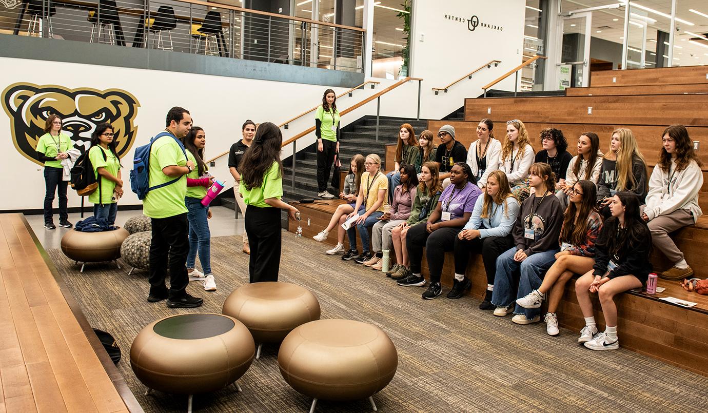 Summer camp instructors talk to students listening attentively in the Oakland Center