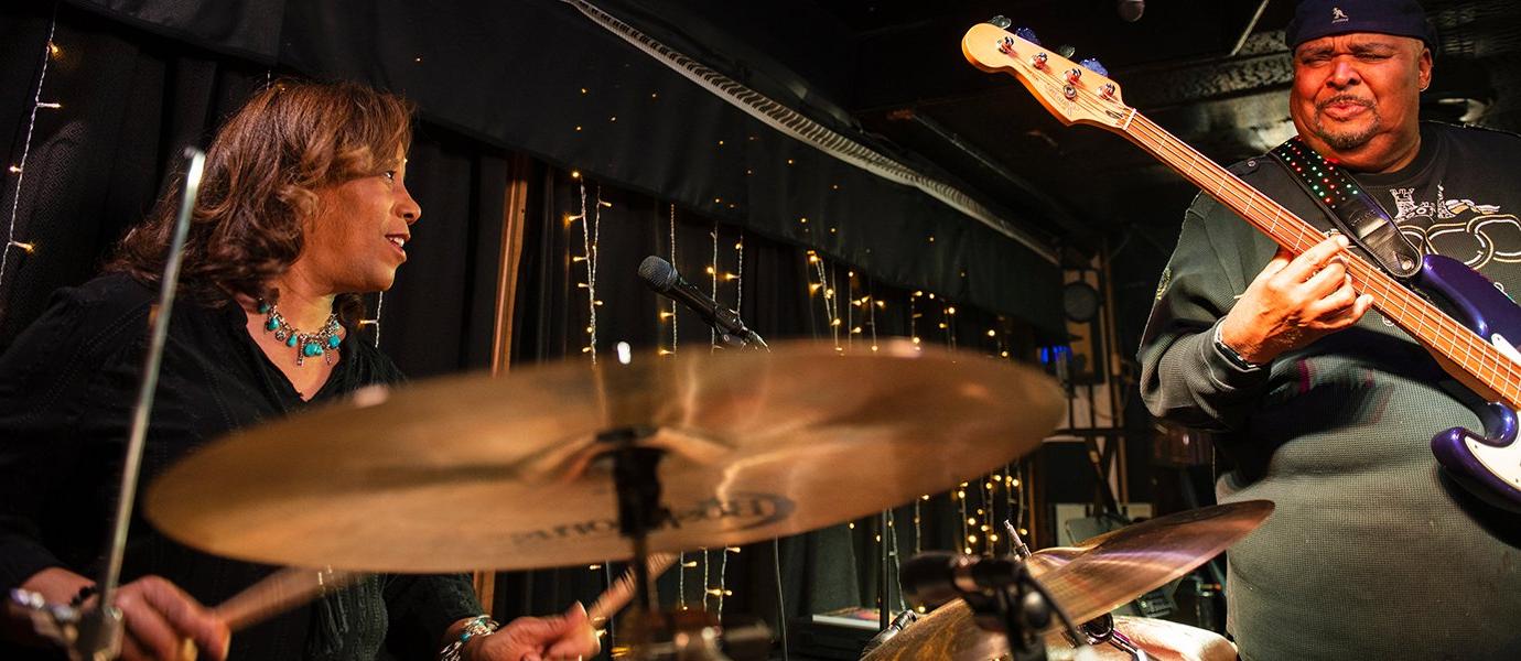 A man playing bass and a woman playing drums