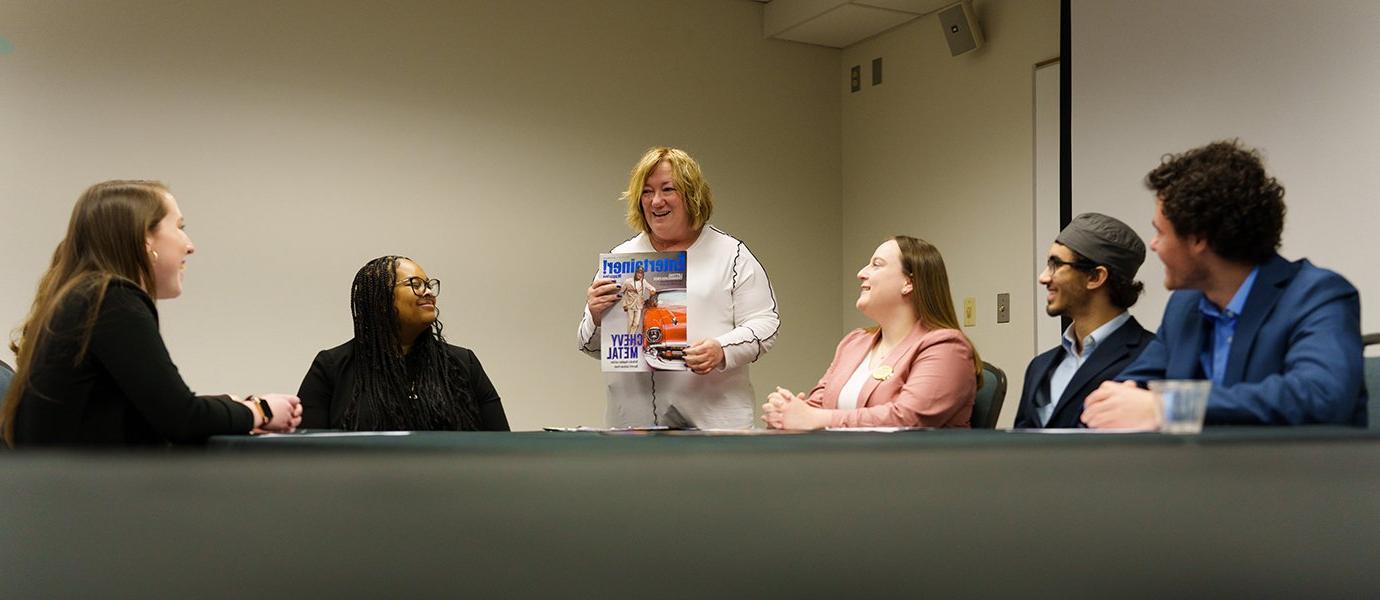 Woman standing with students showing newspaper