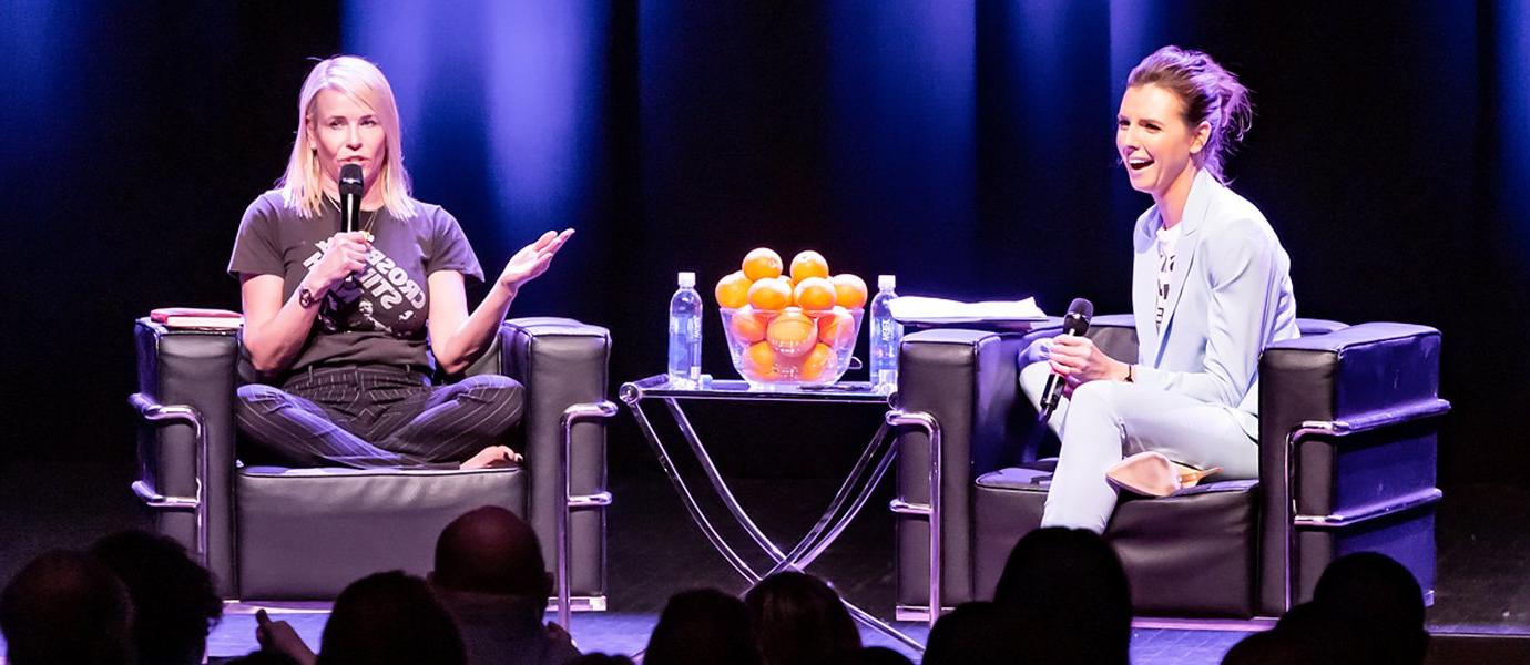 Two women sitting on couches on a stages