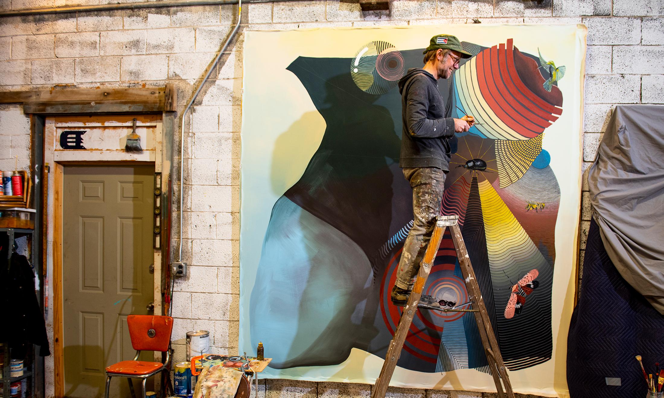 A painter on a ladder in front of his work